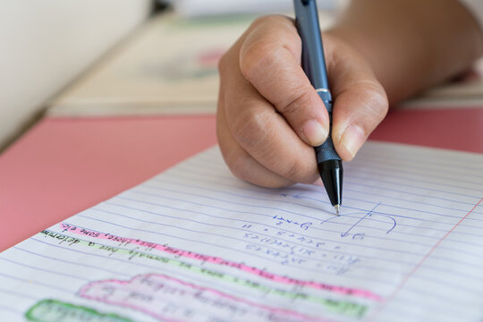 Student learning Maths homework exercise book and writing note testing mathematics in exam, taking fill in notebook test at school classroom, evaluation measurement in education