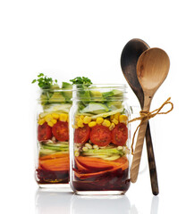 Healthy homemade salad with fresh vegetables and sprouts in glass jars on a white...
