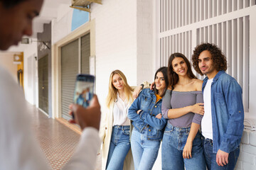 Multi-ethnic group of friends taking photos with a smartphone in the street.