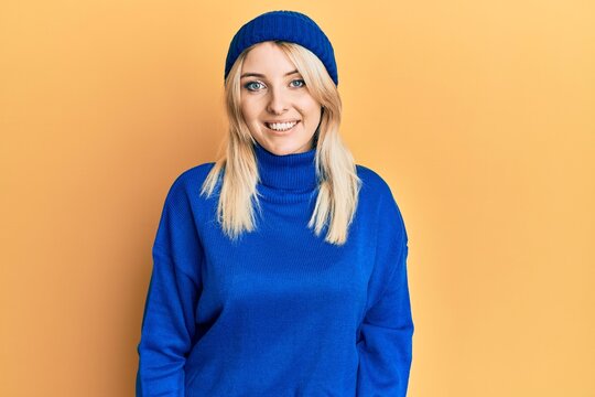 Young caucasian woman wearing wool winter sweater and cap with a happy and cool smile on face. lucky person.