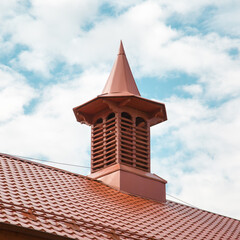 The tower is wooden with a sharp dome of brown color of an old building. Architecture design details construction.