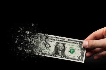 Inflation, dollar hyperinflation with black background. One dollar bill is sprayed in the hand of a man on a black background. The concept of decreasing purchasing power, inflation.
