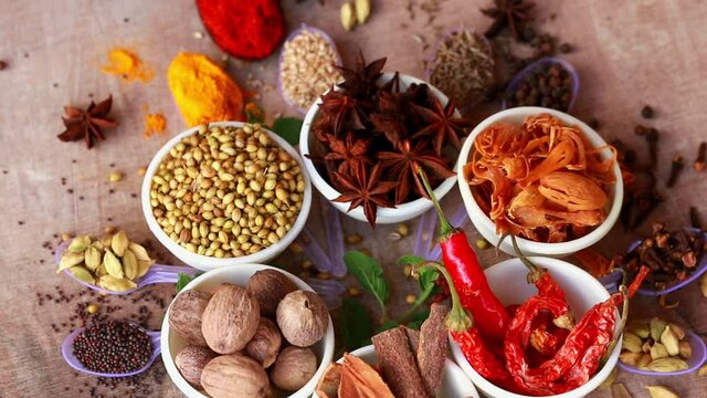 Curry Masala Powder with ingredients,Cumin, Curry, Peppers and Chilli - Delicious Meals,nutmeg,mace,different Indian Spices rotated on wooden table,