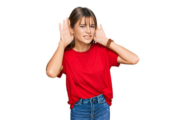 Obraz na płótnie Canvas Teenager caucasian girl wearing casual red t shirt trying to hear both hands on ear gesture, curious for gossip. hearing problem, deaf