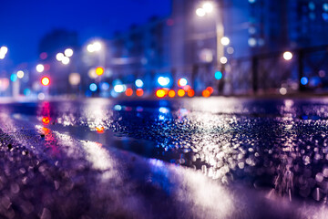 Rainy night in the big city, the empty road with puddles. Close up view from the level of the dividing line