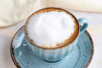 Foam cappuccino on a white wooden background