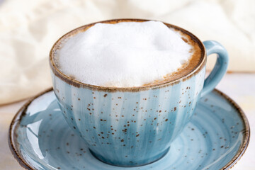 Foam cappuccino on a white wooden background