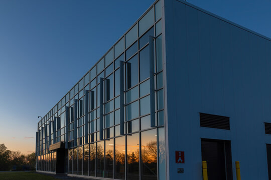 Low-rise Commercial Or Institutional Building Glass And Aluminum Facade At Dusk With Sunset Reflecting On Windows, Security Cameras, Nobody