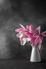 Pink magnolia flowers bouquet in vase on black background. wedding or holiday concept. vertical orientation