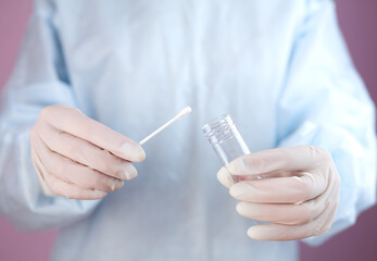 Coronavirus test. Doctor or nurse in medical gloves holds test tube and cotton swab for a test to check for bacteria and viruses. Close-up.