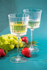 Glass of white wine, bunch grapes. Sun lught and shadow tropic background. Organic antioxidant beverage.
