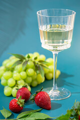 Glass of grape juice, bunch grapes. Sun lught and shadow tropic background. Organic antioxidant beverage.