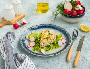 Tuna steak in a sesame crust with fresh salad on a blue ceramic plate on a light background concrete. Fish, seafood recipes