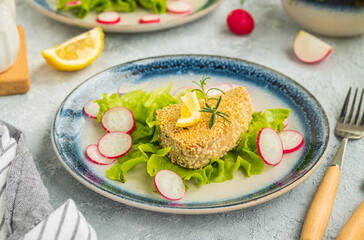 Tuna steak in a sesame crust with fresh salad on a blue ceramic plate on a light background concrete. Fish, seafood recipes
