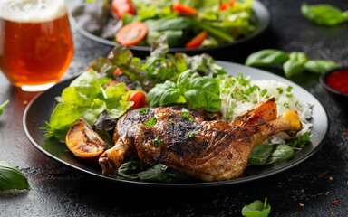 Slow cooked aromatic duck legs with basmati rice and side salad served with orange wedges on black plate