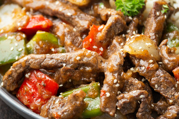Stir fry Chinese pepper beef steak with onion, red and green bell pepper, rice in bowl