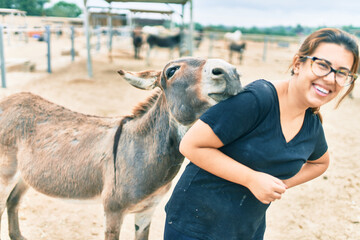 Hispanic woman playing with donkey at the farm.