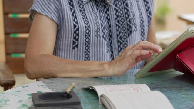 senior woman learn to write Chinese calligraphy from internet - Powered by Adobe
