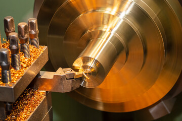 The operation of lathe machine cutting the brass shaft material. The metalworking process by turning machine.