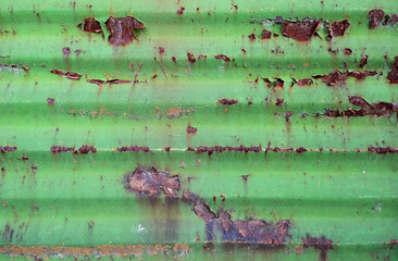 old wavy metal door gate of a garage painted in green color, damaged and weathered - steampunk...