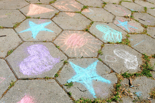 children's drawings of hearts, stars and sun with colored chalk on the street salary with hexagonal tiles together as in a beehive