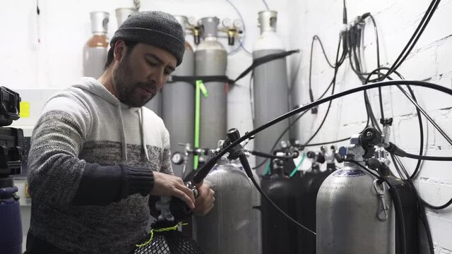 Hispanic diver man working inside filling station at diving workshop center - Focus on man face