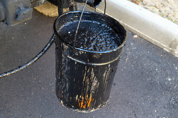 Road works for laying asphalt. Full bucket of bitumen © Petronele