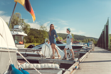 Obraz premium Mother and son entering a motorboat sitting in the harbor