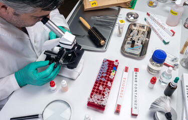 police scientist examines victim's hair under microscope in crime lab, conceptual image