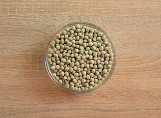 Bowl of raw green peas on a wooden table