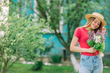 Beautiful young woman with blond hair in a hat with blooming lil