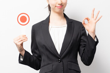白バックの前に立って、OKのプラカードを持つビジネスウーマン