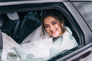 wedding: happy beautiful bride in the car with hairstyles and bright makeup. woman in white dress on the wedding day waiting for the groom and posing. Happiness and love concept.