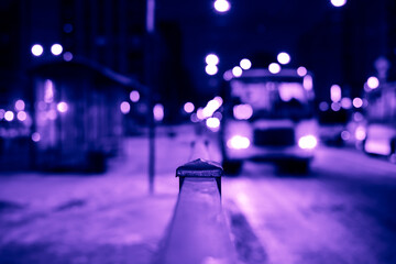 Winter night in the big city, the bus arrives at the bus stop. Close up view from the handrail on...