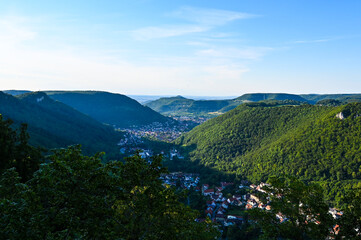 Naklejka na ściany i meble Scenic view of forested mountains of the Schwäbische Alb. The villages of Lichtenstein and Honau are located in the middle of the valley.