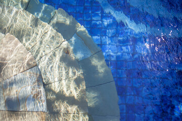 Defocused steps of a swimming pool under blurred blue crystal water ripples