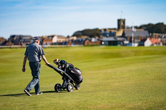 North Berwick Golf Club. Player with golf hole and golf cart. Sunny day with blue sky.