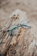 Womens beautiful glasses lie on a narrow beam on the beach on a blurred background