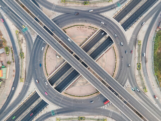 Aerial view of road intersection with roundabout. Urban highway interchange with cars speeding. Junction network of transportation taken by drone.