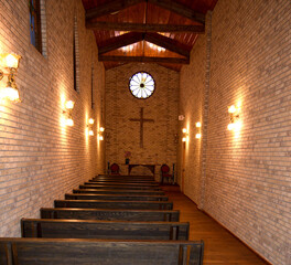 An inside view of an old western prairie church showing neatly lined pews and the cross in the background.