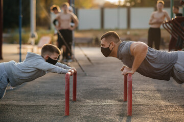 Fototapeta premium Father and son play sports on the sports field in masks during sunset. Healthy parenting and healthy lifestyle