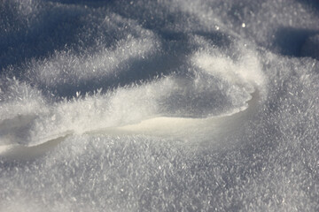 Sunny winter day. Ice is covered with snow. Snow is covered with hoarfrost crystals. Abstract play of light and shadow.