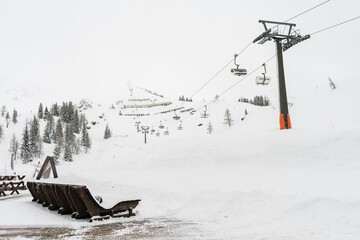 Fototapeta premium Austria, Flachau. Perfect place for winter vacation. View on foggy hill with bench and chair lift. Fairy tale place.