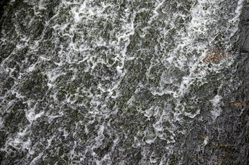 water flowing over black stones of a weir