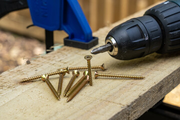 cross head countersunk brass single thread wood screws on a wooden board plank with an electric...