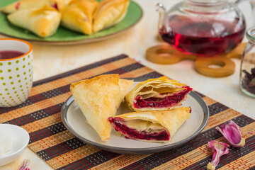 Filo dough triangles with berry filling on a light concrete background.