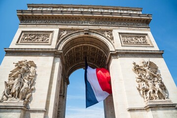French flag waving under Arc de Triomphe in honor of VE day. Facade view. Paris, France. 