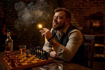 Man smokes a cigar, smoker leisures at chessboard