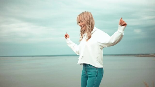 A gorgeous blonde girl happily dances and laughs while