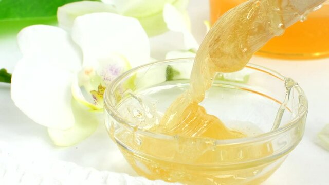 Sugar paste in a transparent jar on a white background. A master stir the sugar paste before removing unwanted hair. Sugaring. Depilation. Epilation. Beauty concept.